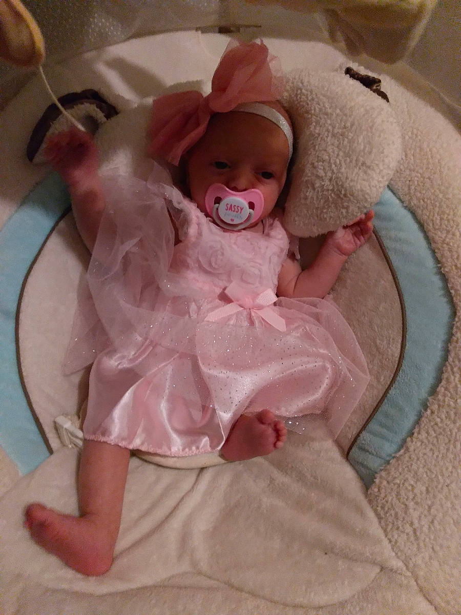 Chloe is registered to the contest to win money with this photo: baby, baby_products, baby_sleeping, baby_toddler_clothing, cheek, comfort, dress, eye, head, headgear, headwear, human_body, infant_bed, iris, linens, magenta, person, pink, skin, sleeve