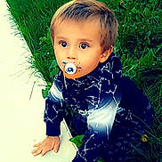 Mayron a rejoint le concours — aidez-le/la à gagner de superbes lots ! child, toddler, pacifier, grass, greenery, outdoor, curious, young_child, nature, plants, dandelions, clothing, hoodie, hands, face, eyes, blond_hair, casual_wear, crawling, sidewalk