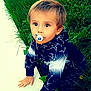 child, toddler, pacifier, grass, greenery, outdoor, curious, young_child, nature, plants, dandelions, clothing, hoodie, hands, face, eyes, blond_hair, casual_wear, crawling, sidewalk