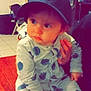 Mayron a rejoint le concours — aidez-le/la à gagner de superbes lots ! baby, child, indoor, cap, hat, polka_dot, pajamas, sitting, person, face, hand, curious, clothing, floor, wood, furniture, home, casual, portrait, young