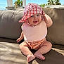 baby, child, hat, bib, smile, outdoor, sofa, cushion, sunlight, happy, blue_eyes, legs, feet, skin, clothing, summer, vacation, palm_trees, relaxation, portrait