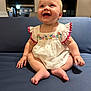 Freya joined the competition — help win amazing prizes! baby, child, smiling, dress, white_dress, embroidered, sitting, couch, blue_couch, indoor, happy, cute, infant, cross_legged, short_hair, pink_trims, face, hands, feet, portrait