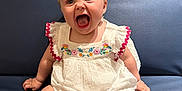 Freya joined the competition — help win amazing prizes! baby, child, sitting, white_dress, embroidery, blue_couch, indoor, happy, expression, barefoot, cute, infant, person, furniture, smiling, small_hands, small_feet, portrait, young_child, cheerful