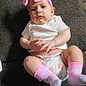baby, infant, pink_bow, headband, white_shirt, diaper, pink_socks, striped_socks, couch, gray_couch, fabric, person, child, hands, legs, cute, portrait, indoor, expression, sitting