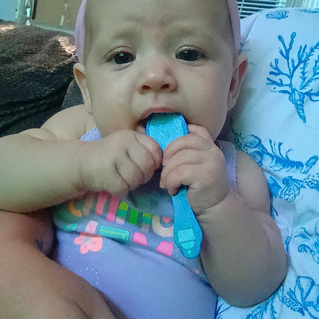 Esmerella joined the competition — help win amazing prizes! baby, child, headband, pink_bow, blue_object, hand, blanket, air_conditioner, indoor, person, clothing, sitting, cute, infant, holding, face, expression, comfort, home, portrait