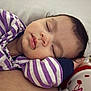 baby, sleeping, face, child, purple_striped_clothing, peaceful, closeup, infant, cute, soft_lighting, portrait, resting, cozy, serene, young_child, skin, eyelashes, head, comfort, indoor