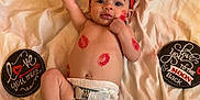 Lainey is registered to the contest to win money with this photo: baby, infant, diaper, red_headband, lipstick_marks, blanket, love_sign, moon_sign, smiling, lying_down, cute, face, hand, foot, skin, cheek, playful, happy, indoors, soft_texture