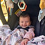 baby, blanket, car_seat, child, toy, smile, face, indoors, clothing, infant, hand, pink, fabric, plaything, seatbelt, cute, young_child, mickey_mouse, happy, portrait