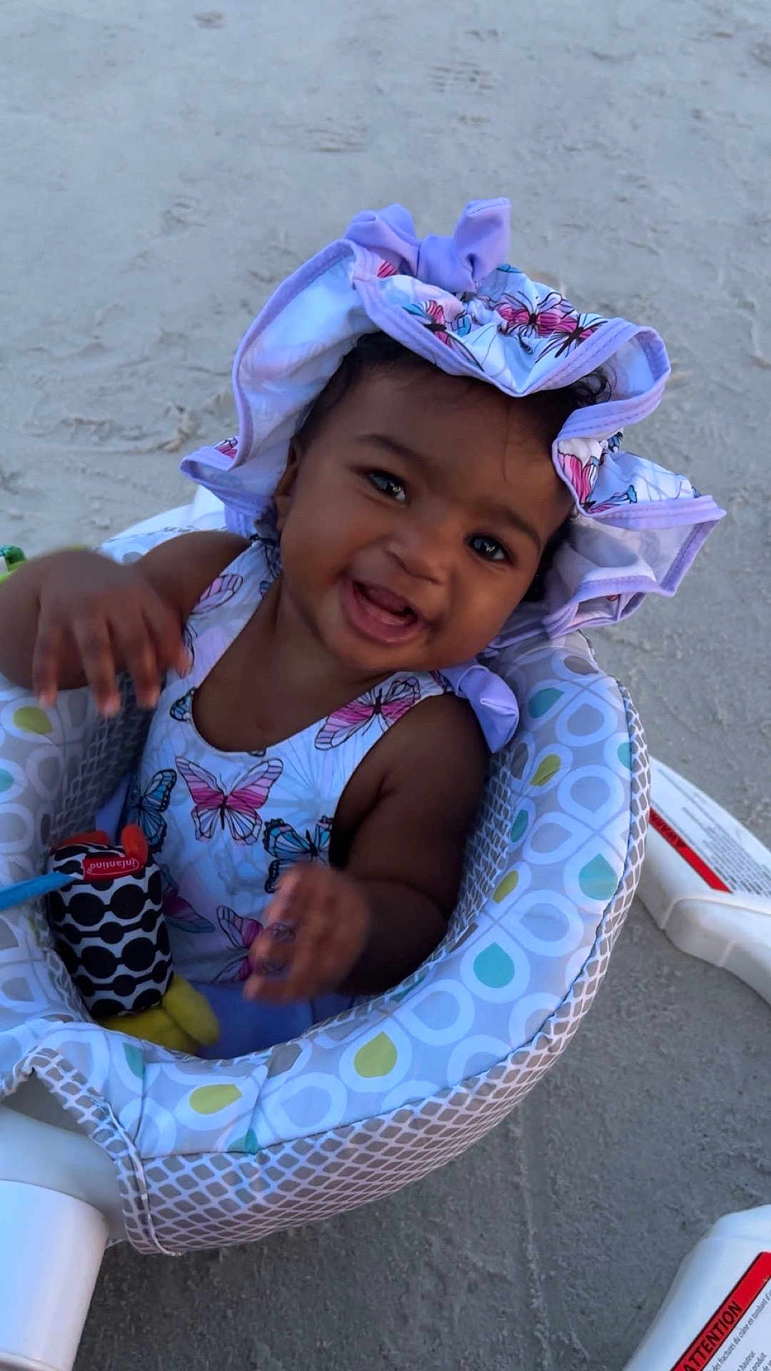Ilyes joined the competition — help win amazing prizes! baby, child, smiling, hat, butterfly_pattern, toy, baby_seat, outdoor, sand, happy, infant, clothing, cute, playful, sun_hat, seat, person, portrait, young_child, summer