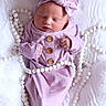 Raylan is registered to the contest to win money with this photo: newborn, baby, sleeping, pink_clothing, headband, bow, white_beads, blanket, soft_texture, infant, cute, portrait, peaceful, hands, face, closeup, cozy, resting, small, adorable