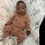 Kaylani is registered to the contest to win money with this photo: baby, blanket, brown_outfit, bunny_pattern, child, cozy, cute, fashion, footwear, happy, headband, indoors, infant, lying_down, paw_prints, portrait, smiling, sneakers, soft_texture, toddler