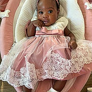 Kaylani joined the competition — help win amazing prizes! baby, infant, child, dress, pink, lace, headband, socks, footwear, baby_seat, fabric, lace_trim, cute, portrait, indoor, person, young_child, fashion, smile, comfortable
