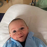 Thiago participe au concours pour gagner de l'argent avec cette photo : baby, child, indoor, blue_jacket, cushion, face, smile, eyes, person, portrait, furniture, door, floor, home, cozy, clothing, head, expression, infant, cute