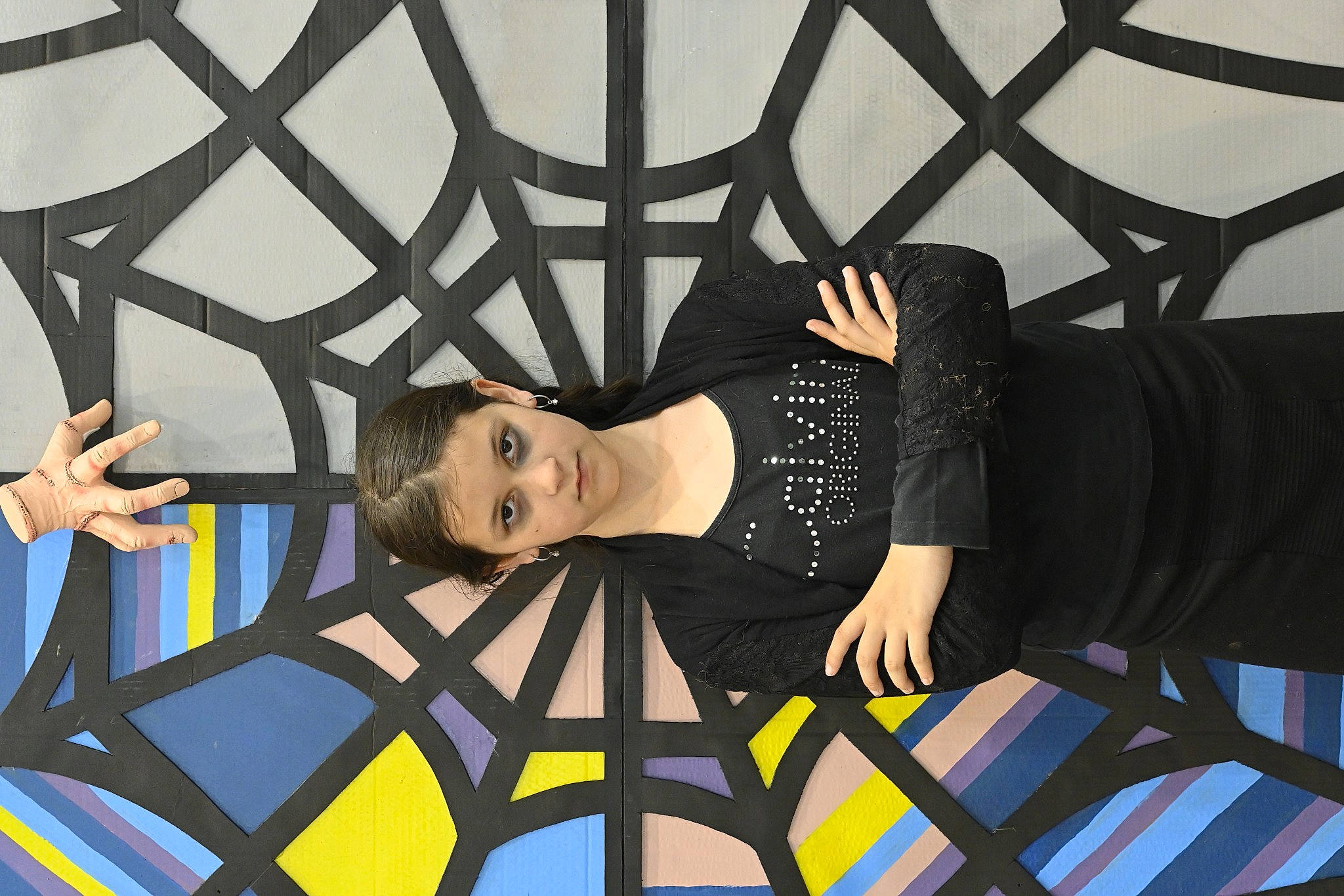 Lucy participe au concours pour gagner de l'argent avec cette photo : art, black_hair, ceiling, entertainment, event, eyewear, fashion_design, fun, leisure, pattern, performance, person, room, sitting, t_shirt, thigh, visual_arts, wood