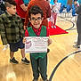 child, certificate, school, gym, award, people, indoor, floor, shoes, glasses, clothing, red_carpet, group, celebration, person, smile, tie, wood_floor, background, event