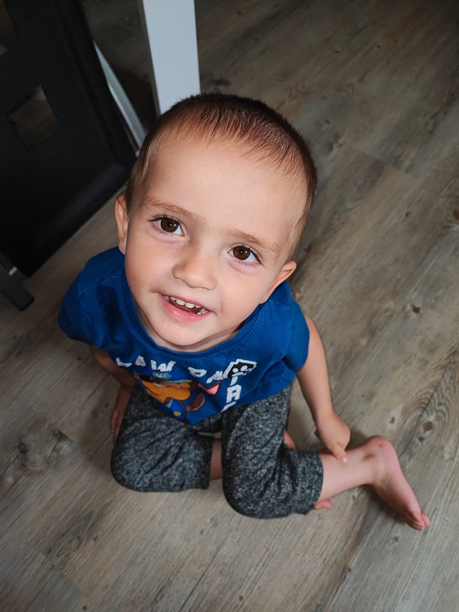 Mathis a rejoint le concours — aidez-le/la à gagner de superbes lots ! baby_toddler_clothing, cheek, child, electric_blue, flash_photography, floor, flooring, fun, happy, hardwood, joy, laminate_flooring, person, portrait_photography, sitting, smile, t_shirt, toddler, varnish, wood