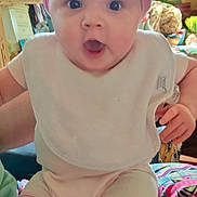 Lani is registered to the contest to win money with this photo: baby, infant, pink_headband, bib, striped_leggings, wide_eyes, surprised_expression, chubby_cheeks, cute, closeup, sitting, indoor, living_room, lamp, blanket, toy, furniture, portrait, colorful, person