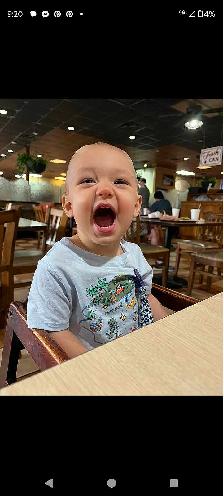 Carter joined the competition — help win amazing prizes! toddler, child, high_chair, restaurant, wooden_chair, table, smiling, happy, indoors, casual_clothing, cute, baby, person, mouth_open, dining, food_court, seated, daylight, expression, playful
