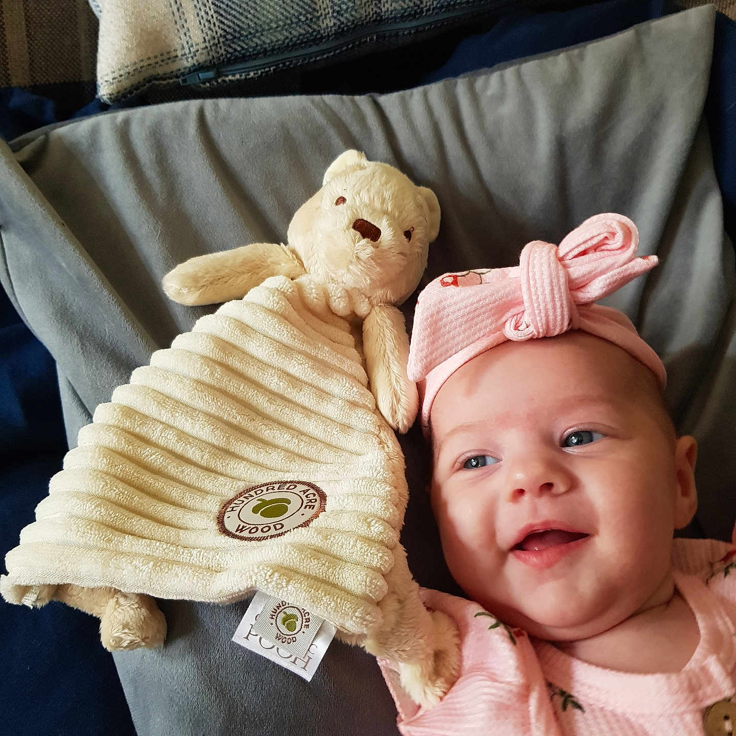 Isabella joined the competition — help win amazing prizes! baby, blanket, child, cozy, cushion, cute, fabric, face, happy, headband, indoor, infant, lying_down, pink_clothing, portrait, smile, soft_toy, stuffed_animal, teddy_bear, toy