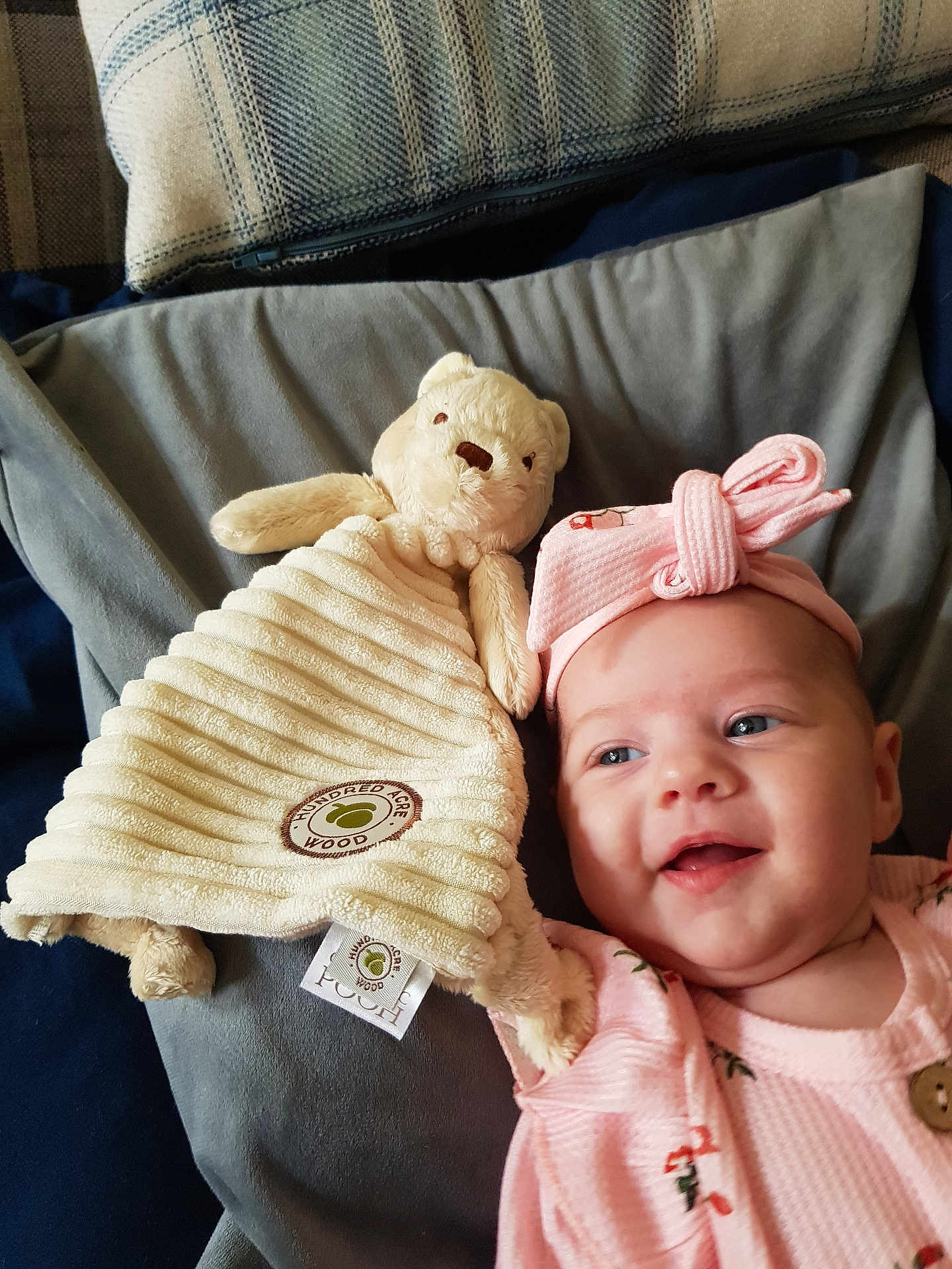 Isabella joined the competition — help win amazing prizes! baby, smile, headband, pink_clothing, teddy_bear, stuffed_animal, blanket, cushion, fabric, indoor, child, soft_toy, happy, cute, infant, portrait, face, cozy, lying_down, toy