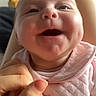 baby, infant, smiling, happy, cute, pink_clothing, hand, face, chubby_cheeks, closeup, indoor, holding_hand, portrait, child, person, cute_outfit, fingers, wooden_chair, expression, joyful