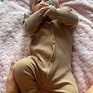 Maeve is registered to the contest to win money with this photo: baby, infant, onesie, pacifier, blanket, hand, foot, soft_texture, bed, sleepwear, person, child, cute, lying_down, resting, indoor, skin, comfort, care, toddler