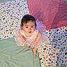 baby, child, tutu, pink_dress, playmat, colorful, patterned, floor, pillow, shadow, curly_hair, looking_up, barefoot, indoors, cute, infant, playtime, bright, soft_lighting, smiling