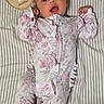 baby, infant, two_months, child, portrait, lying_down, striped_blanket, floral_outfit, onesie, sleepwear, smiling, open_mouth, raised_arms, fists, wooden_milestone, number_two, nursery, indoors, cute, photography