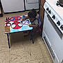 Amir is registered to the contest to win money with this photo: appliance, cabinet, casual, chair, child, curly_hair, floor, furniture, indoor, kitchen, person, refrigerator, seat, small_table, snack, spiderman, stove, table, tile_floor, toddler