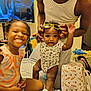 Amir is registered to the contest to win money with this photo: adult, baby, bag, bed, braids, child, clothing, curly_hair, family, furniture, happy, holding, indoor, person, room, sitting, smiling, sock, sunglasses, television