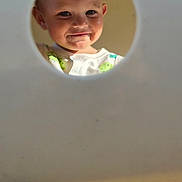 Cain joined the competition — help win amazing prizes! toddler, child, face, smile, food, messy, peek, hole, circular, clothing, shirt, blue_eyes, blond_hair, closeup, portrait, cute, playful, indoor, curiosity, baby