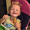 Cain is registered to the contest to win money with this photo: baby, chicken_drumstick, child, curly_hair, eating, family_photo, food, green_bowl, happy, high_chair, indoors, laughing, playful, portrait, seated, shark_shirt, smiling, snack, toddler, tray