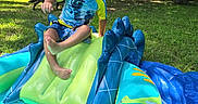 Cain is registered to the contest to win money with this photo: blue, child, curly_hair, dog, fun, grass, inflatable_pool, nature, outdoor, park, person, play, slide, summer, sunlight, swimming, toddler, trees, water, yellow