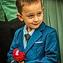 child, boy, suit, blue_suit, red_rose, flower, formal_wear, portrait, smile, hands, tie, button, young_boy, short_hair, standing, indoor, people, fashion, cute, event