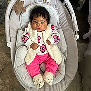 Daniela is registered to the contest to win money with this photo: baby, infant, child, baby_seat, plush_toy, floral_clothing, pink_pants, slippers, fuzzy_vest, cushion, indoor, floor, carpet, cute, relaxed, portrait, baby_accessory, soft_texture, comfortable, cozy