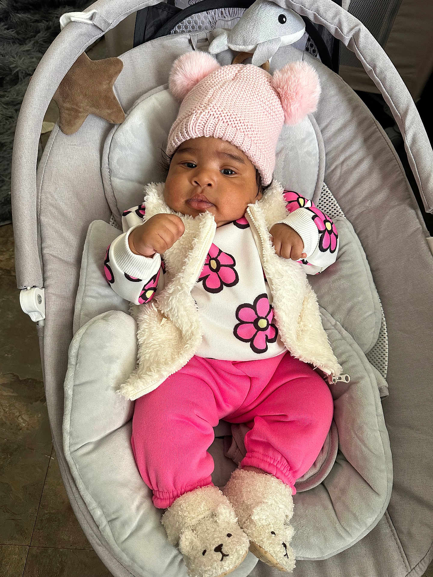 Daniela joined the competition — help win amazing prizes! baby, infant, pink_clothing, hat, pom_pom, baby_seat, fuzzy_vest, slippers, bear_slippers, cute, indoor, floor, plush_toy, star_shaped_pillow, face, hands, footwear, child, person, comfort