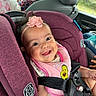 baby, car_seat, smile, pink_bib, headband, avocado_design, car_interior, child, seatbelt, happy, person, clothing, safety_harness, infant, cute, portrait, seat, baby_accessory, car_window, family