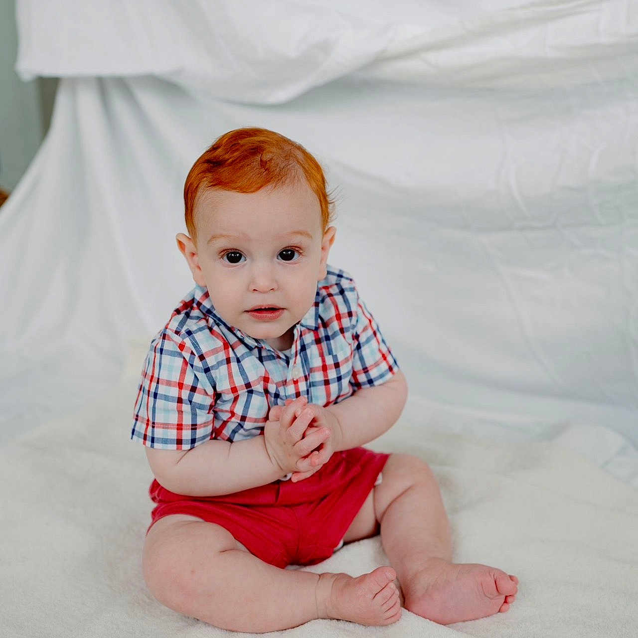 Liam is registered to the contest to win money with this photo: baby, bed, bodypart, clothing, face, finger, furniture, hand, happy, head, indoors, kneeling, pants, person, photography, portrait, shirt, shorts, sitting, t_shirt