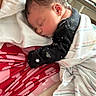 newborn, baby, sleeping, blanket, red_clothing, striped_blanket, infant, resting, cozy, arm, patterned_fabric, closeup, indoors, soft_lighting, peaceful, head, face, person, wrapped, cute