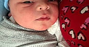Cameron joined the competition — help win amazing prizes! newborn, baby, infant, swaddled, blanket, beanie, blue_hat, red_fabric, heart_pattern, close_up, face, sleeping, peaceful, soft_lighting, cozy, cute, child, portrait, indoor, resting