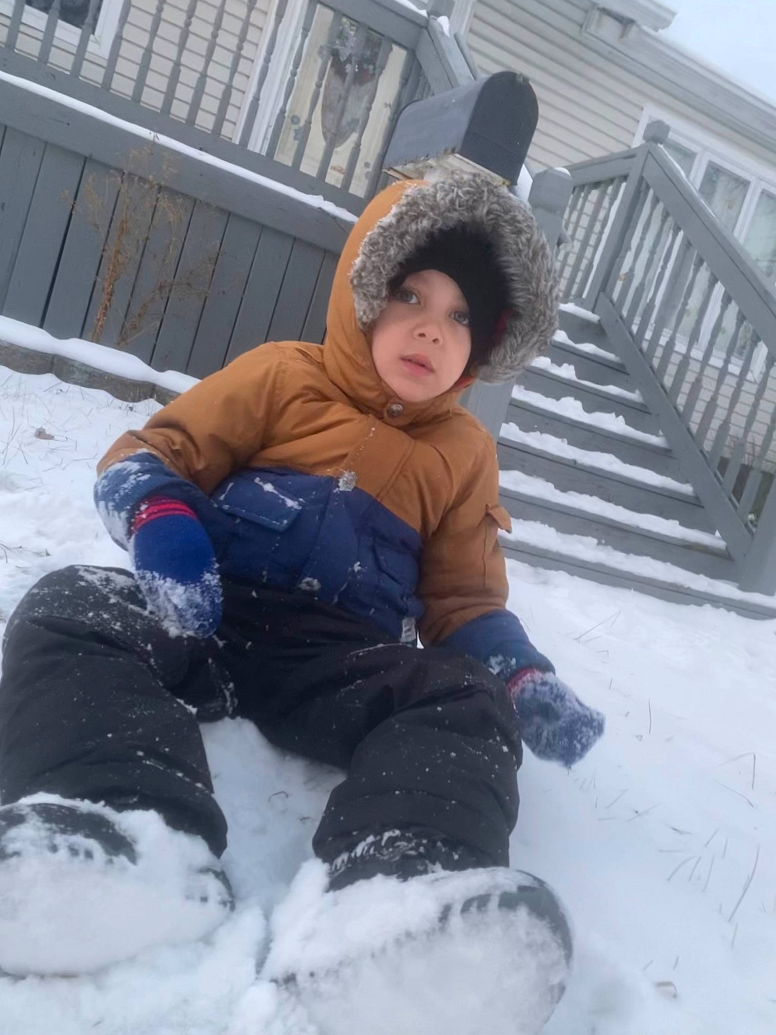 Izaiah is registered to the contest to win money with this photo: boot, cap, child, event, freezing, fun, fur, glove, headwear, jacket, knit_cap, parka, person, playing_in_the_snow, precipitation, recreation, sitting, sky, snow, snow_boot