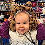 accessories, apparel, baby, child, clothing_store, cute, earmuffs, face, fashion, happy, hat, indoor, knitted, leopard_print, purple_sweater, shopping_cart, smiling, toddler, white_vest, winter_clothes