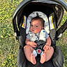 baby, infant, child, car_seat, stroller, outdoor, grass, sunlight, portrait, face, eyes, sitting, harness, safety_strap, blanket, clothing, bare_feet, comfortable, daylight, photography