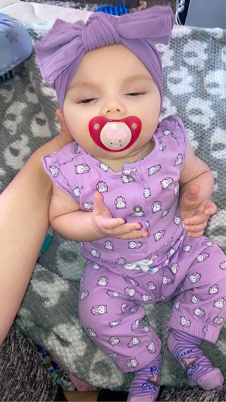 Eliza is registered to the contest to win money with this photo: baby, baby_toddler_clothing, cap, cheek, eye, face, fun, happy, headwear, human_body, iris, lip, nose, person, pink, purple, skin, sleeve, smile, textile