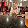 Vincent joined the competition — help win amazing prizes! baby, child, smiling, reflection, countertop, indoor, people, chairs, drink, conversation, casual_clothing, light_fixture, table, hand, red_jacket, cap, phone, restaurant, window, exit_sign