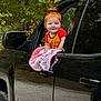 Evalyna is registered to the contest to win money with this photo: baby, child, red_hair, blanket, car, truck, window, outdoor, trees, greenery, smiling, person, vehicle, automobile, cheerful, portrait, cute, small_child, casual_clothing, nature