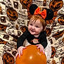 baby, child, red_hair, balloon, headband, bat_wings, mouse_ears, smiling, halloween, pumpkin, blanket, costume, orange, black_clothing, cute, sitting, indoor, holiday, festive, joyful