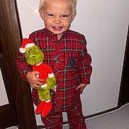 Nayte participe au concours pour gagner de l'argent avec cette photo : child, pajamas, plush_toy, grinch, red, blue, smile, indoor, carpet, door, wood, toy, footwear, cute, happy, person, clothing, standing, holiday, face