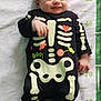 Lucas participe au concours pour gagner de l'argent avec cette photo : baby, infant, smiling, onesie, skeleton_costume, black_clothing, lying_down, blanket, measurement_markings, cute, candy, heart, green, white_background, child, portrait, happy, baby_clothes, crawling_mat, indoors