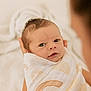 baby, swaddled, blanket, newborn, infant, person, face, eyes, hands, soft_focus, patterned_blanket, cradle, closeup, warmth, skin, head, expression, indoor, parent, care